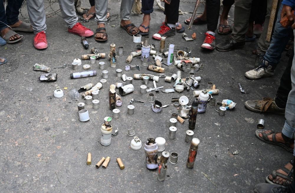 Kashmiri protesters stand around empty shells and canisters fired by Indian government forces during clashes at Mirgund Pattan on the outskirts of Srinagar on May 13, 2019, as protesters called for justice in the case of the alleged rape of a three-year-o