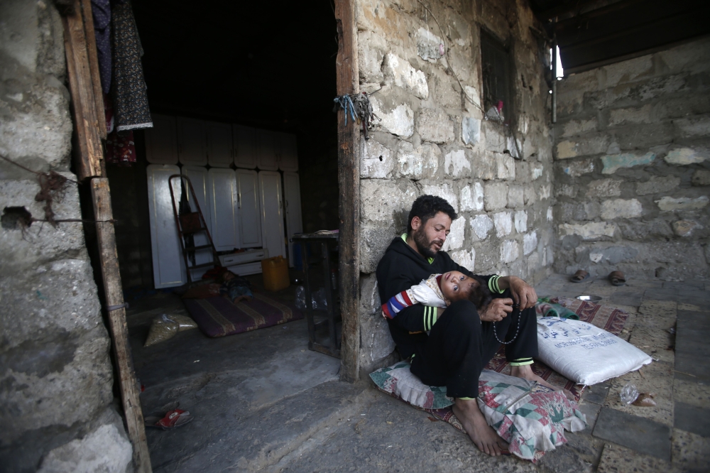 :A Palestinian man with his child on May 13, 2019 in the southern Gaza Strip refugee camp of Khan Yunis. (AFP / MOHAMMED ABED)