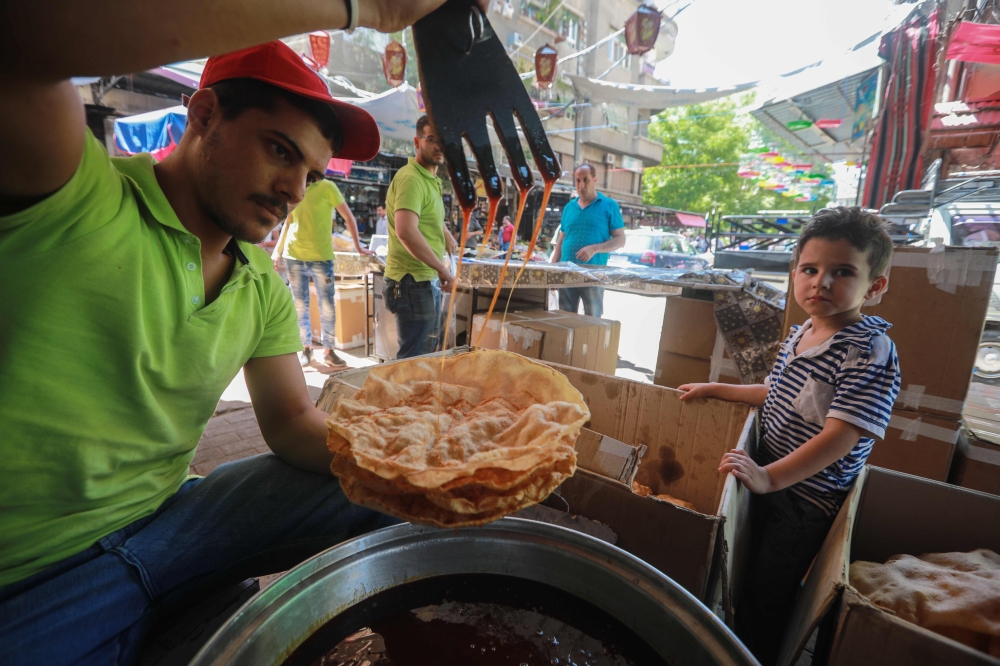 A Syrian vendor prepares sweets at a market in the capital Damascus on May 19 , 2019, during the Muslim holy fasting month of Ramadan. / AFP / LOUAI BESHARA