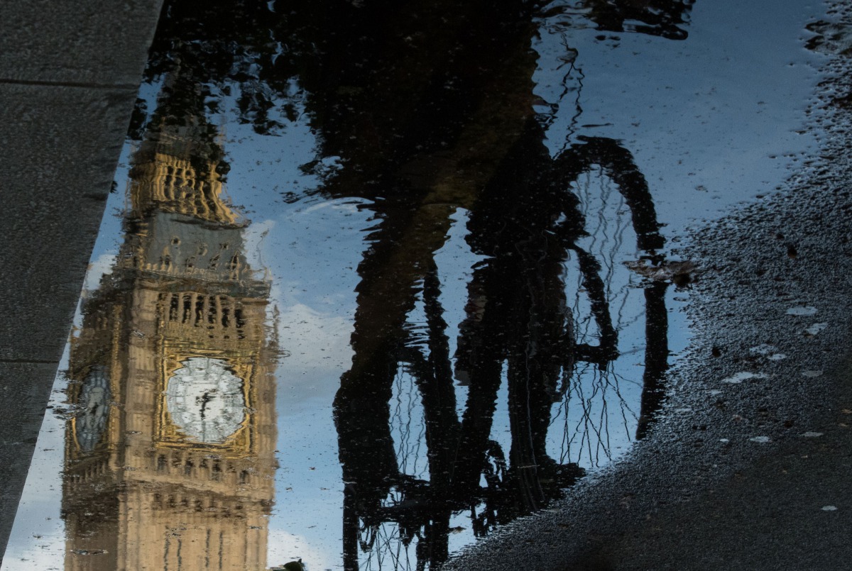 Big Ben is reflected in a puddle as a cyclist rides by in London on 27 June, 2016. AFP/Leon Neal