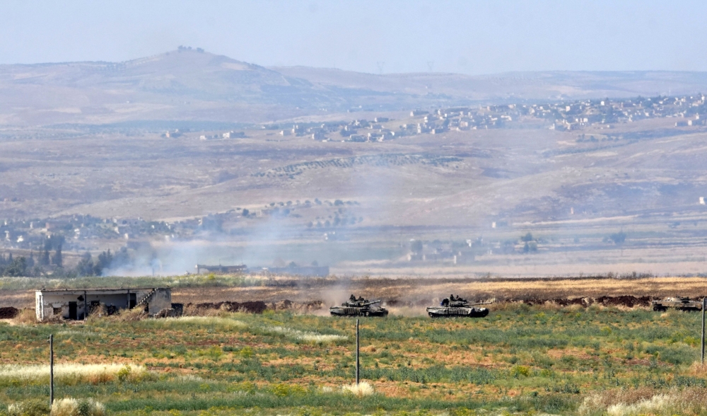Smoke billows above buildings in the town of Kafr Nabuda in the north of the Syrian Hama province during reported air strikes by Syrian regime forces on May 26, 2018.   AFP / George OURFALIAN