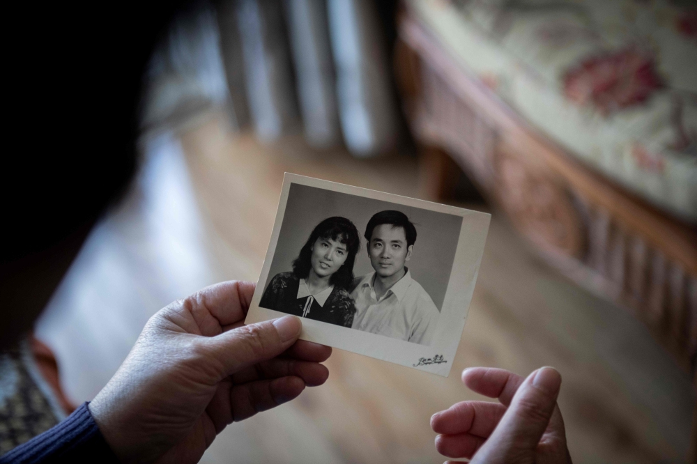 In this picture taken on April 10, 2019, You Weijie, 66, looks at a photograph of her and husband Yang Minghu, in Beijing.  AFP / Nicolas Asfouri