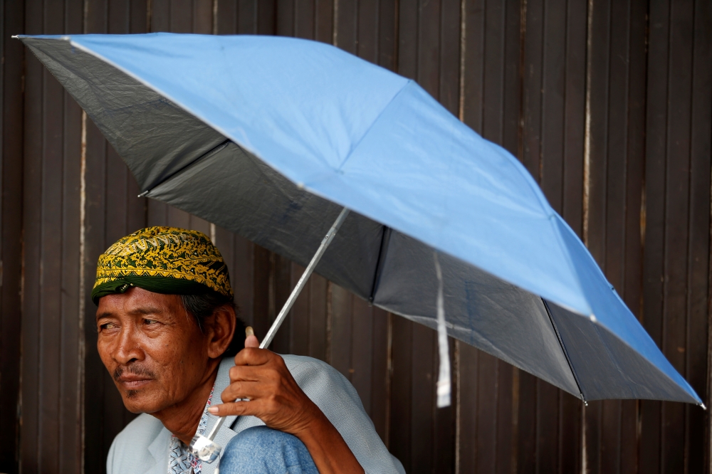 A street vendor uses an umbrella as he waits for customers at a traditional market in Jakarta, Indonesia, June 3, 2019. Reuters/Willy KurniawanAnd a pinch of background.  