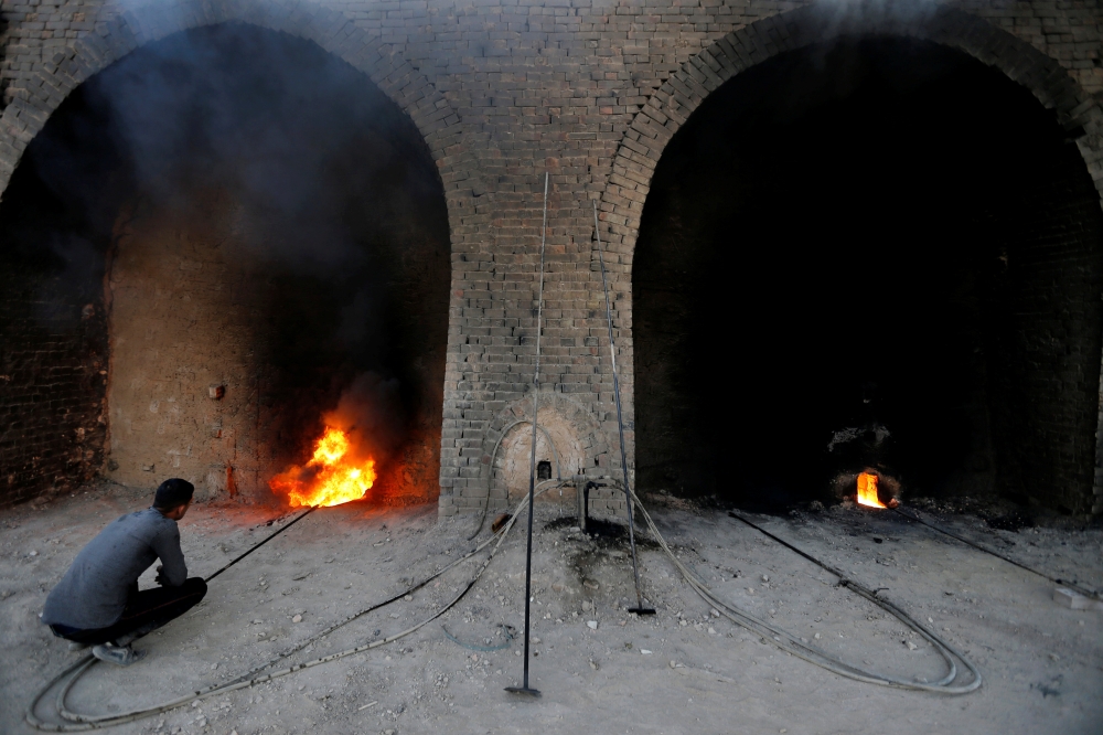 An Iraqi worker checks a chimney stack outlets at the brick factory in the town of Nahrawan in Baghdad, Iraq June 3, 2019. Reuters/Thaier al-Sudani