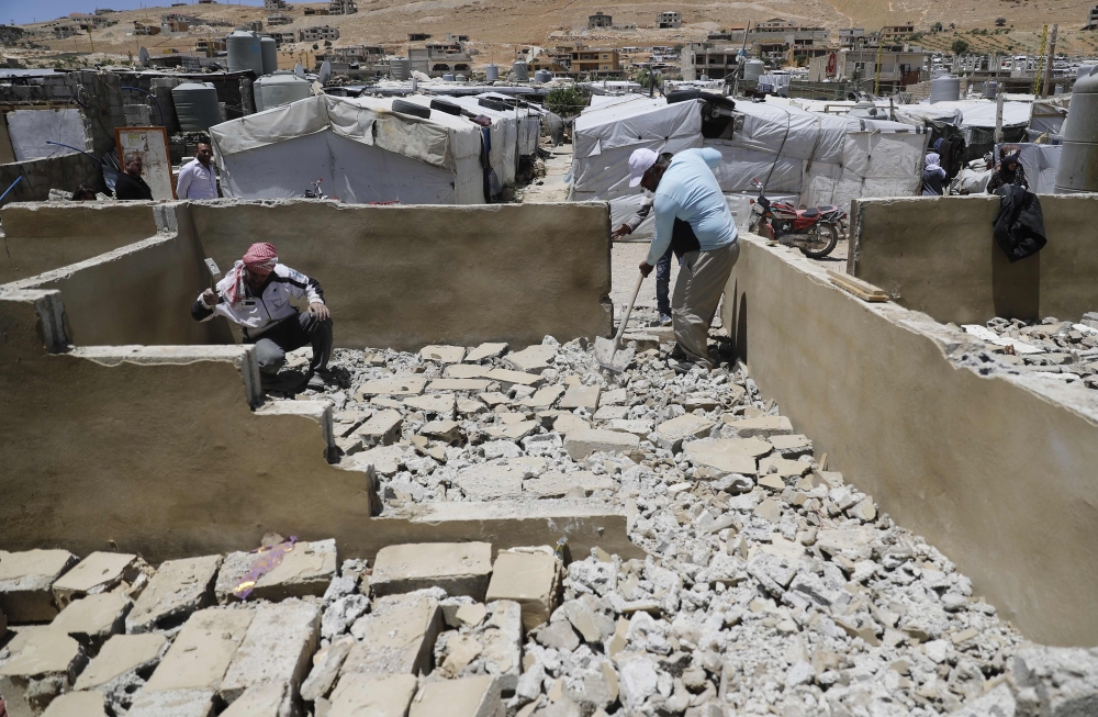 Workers demolishing a concrete shelter at a refugee camp in the northeastern Lebanese town of Arsal, in the Bekaa valley. AFP / JOSEPH EID
