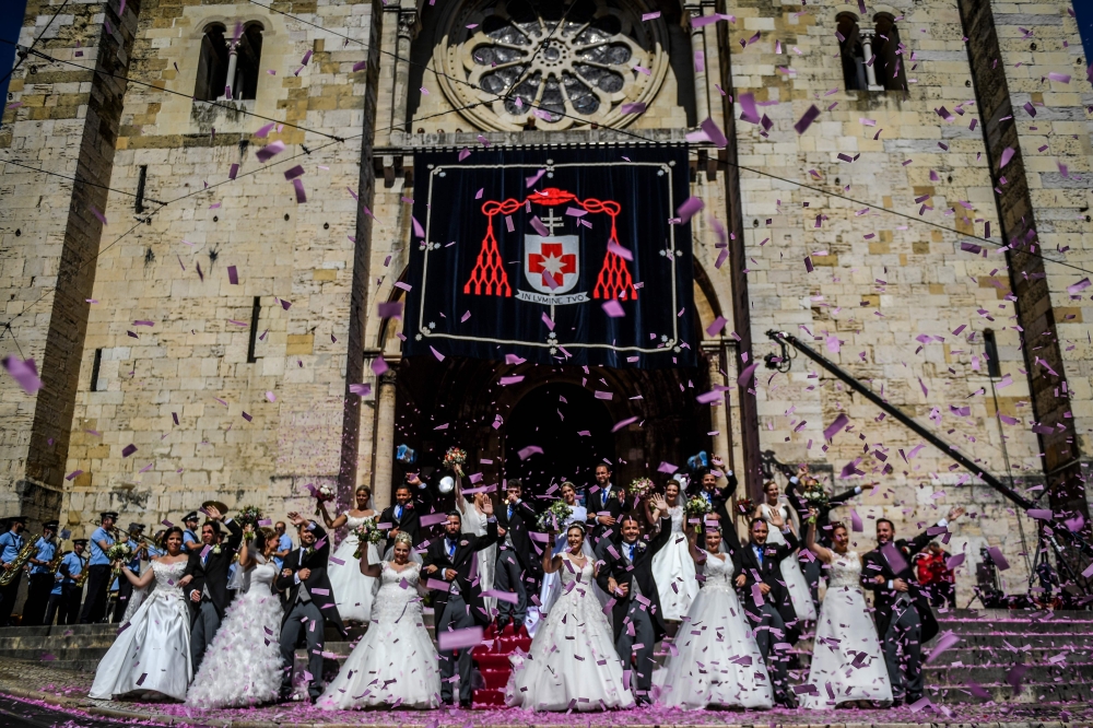 Brides and grooms pose for a photo outside the Lisbon's cathedral following their wedding ceremony in Lisbon on June 12, 2019.