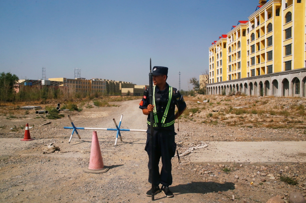 A Chinese police officer takes his position by the road near what is officially called a vocational education centre in Yining in Xinjiang Uighur Autonomous Region, China September 4, 2018. REUTERS/Thomas Peter 
 