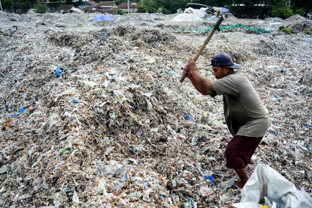 In this picture taken on December 11, 2018 a man searches for plastic waste for resale at a dump in Mojokerto, East Java province. Around 300 million tonnes of plastic are produced every year and end up in landfill or the seas, according to the Worldwide 