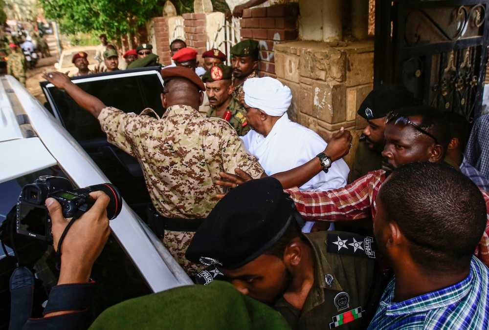 Sudan's ousted president Omar al-Bashir (C) is escorted into a vehicle as he returns to prison following his appearance before prosecutors over charges of corruption and illegal possession of foreign currency, in the capital Khartoum on June 16, 2019. / A