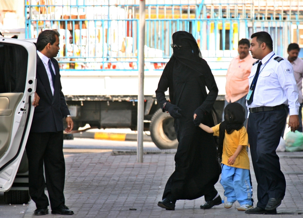 Michael Jackson, wearing an abaya, a traditional Arab women's veil, holds the hand of a child as he is escorted to his car by a shopping mall security agent in Manama, Bahrain, January 25, 2006.