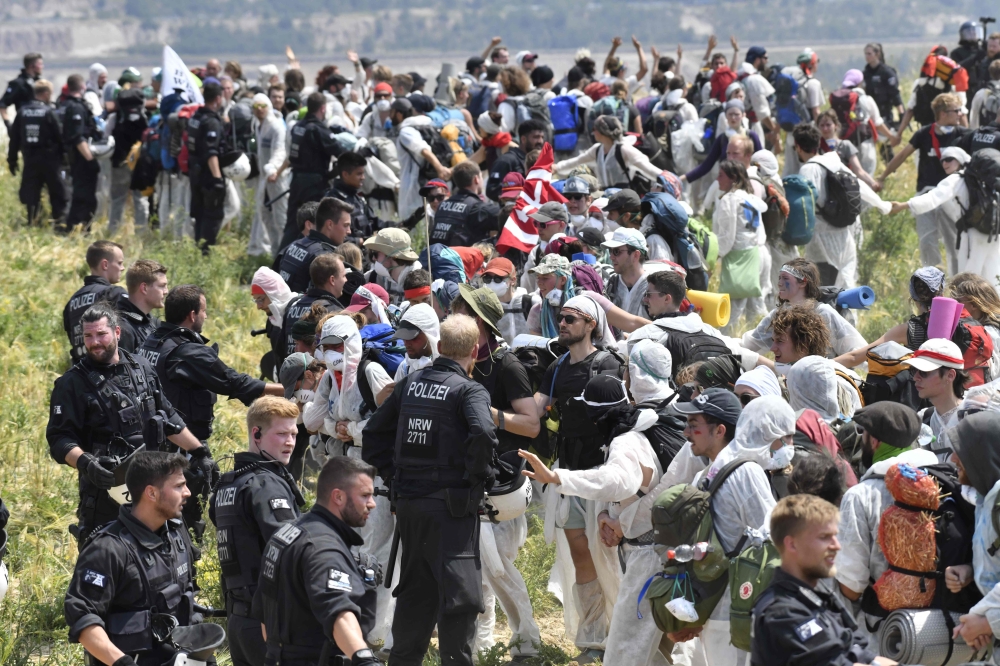 Policemen stand next to anti-coal activists demonstrating at the open-cast mine Garzweiler, western Germany, on June 22, 2019.(AFP / INA FASSBENDER)