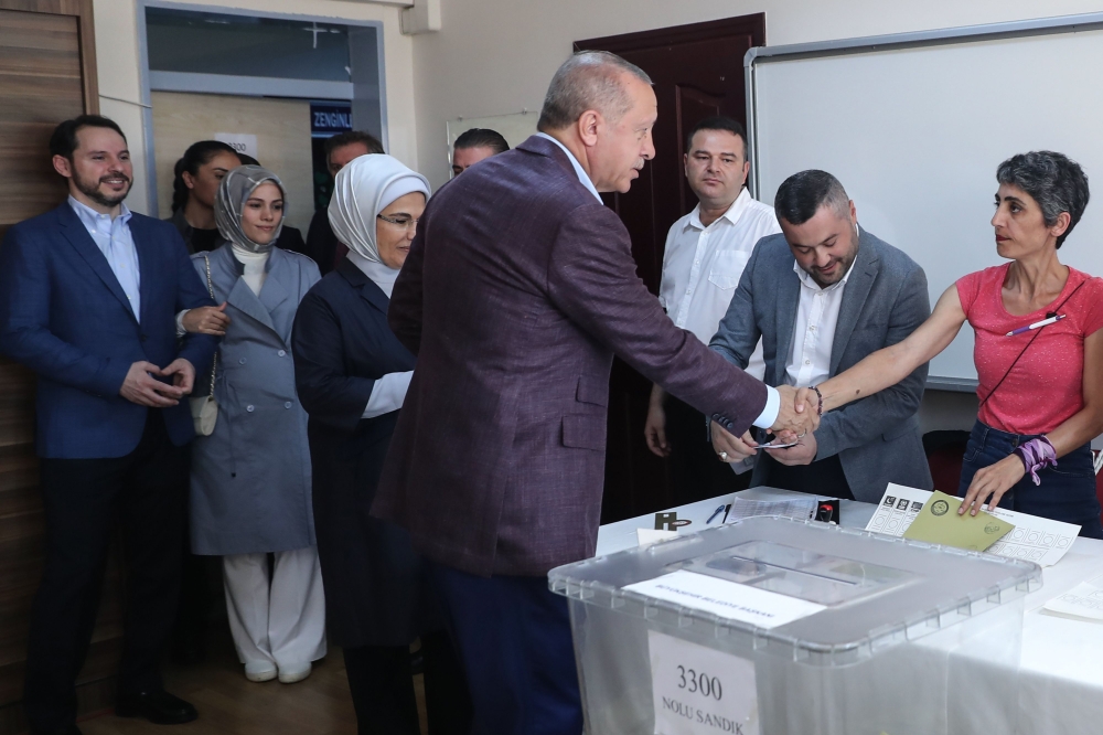 President Recep Tayyip Erdogan (C) shakes hands as he casts his vote, flanked by Finance Minister Berat Albayrak (L) and his wife Esra Erdogan (2nd L), at a polling station during the mayoral election re-run in Istanbul on June 23, 2019.  AFP / Adem ALTAN