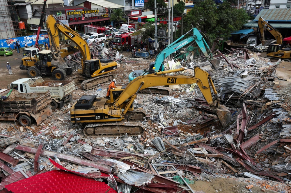 Rescue workers use earthmovers to clear debris as they search for victims a day after an under-construction building collapsed in Sihanoukville on June 23, 2019.   AFP / SUN RETHY Kun