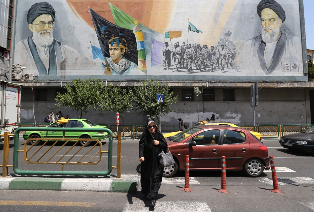 An Iranian woman walks past a mural painting depicting the late founder of the Islamic Revolution Ayatollah Ruhollah Khomeini (R) and Iran's supreme leader Ayatollah Ali Khamenei in the Iranian capital Tehran on June 25, 2019.  AFP / Atta Kenare 
