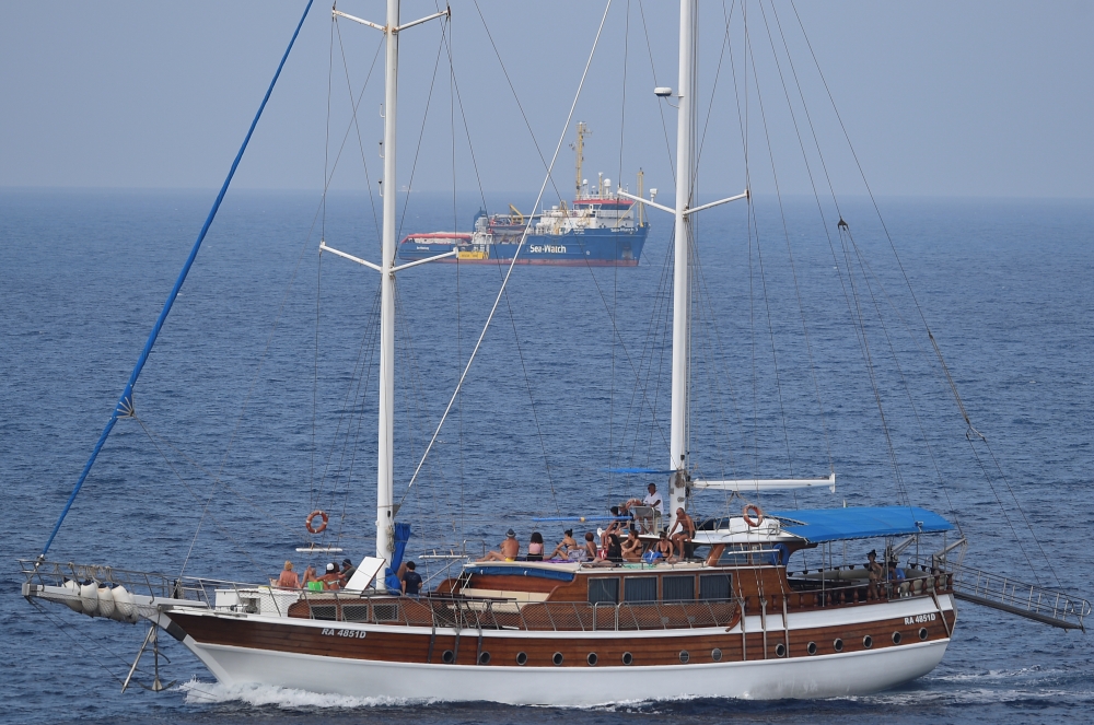 A tourist boat passes by search and rescue ship Sea-Watch 3 as it remains blocked near the island of Lampedusa, Italy, June 28, 2019. Reuters/Guglielmo Mangiapane