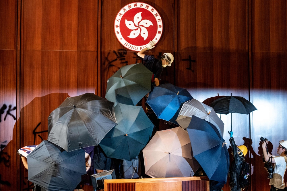A protester defaces the Hong Kong emblem after protesters broke into the government headquarters in Hong Kong on July 1, 2019, on the 22nd anniversary of the city's handover from Britain to China. AFP / Philip Fong 