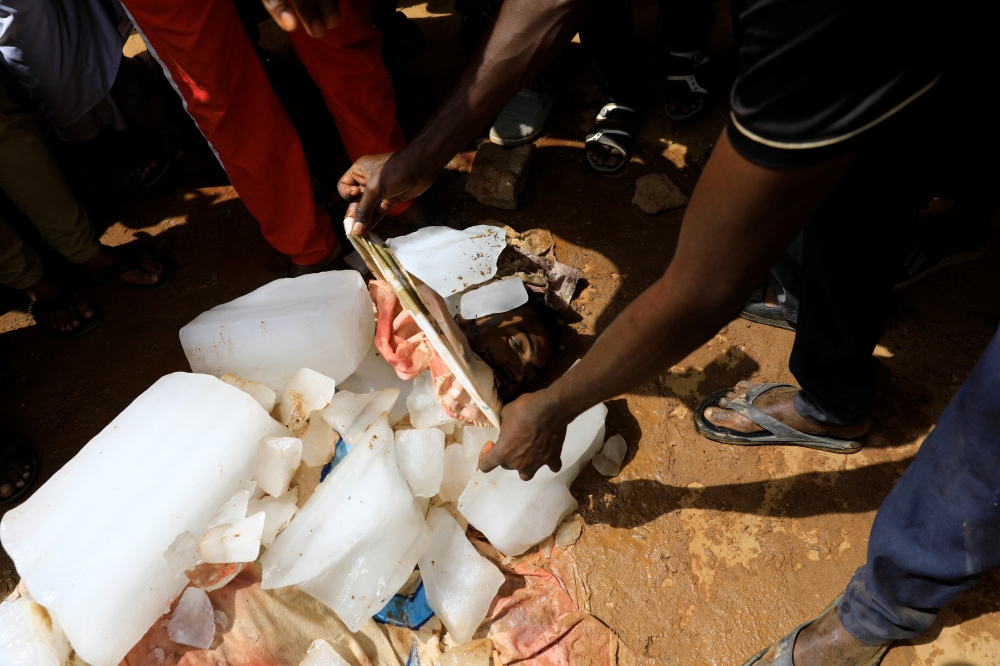 A man checks the face of one of the three Sudanese men riddled with bullets as his body is covered with ice, in the city of Omdurman across the River Nile from Khartoum, Sudan, July 1, 2019. Reuters/Umit Bektas