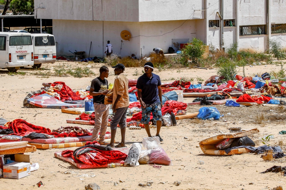  Migrants stand and walk outside at a detention centre used by the Libyan Government of National Accord (GNA) in the capital Tripoli's southern suburb of Tajoura on July 3, 2019, following an air strike on a nearby building that left dozens killed the pre