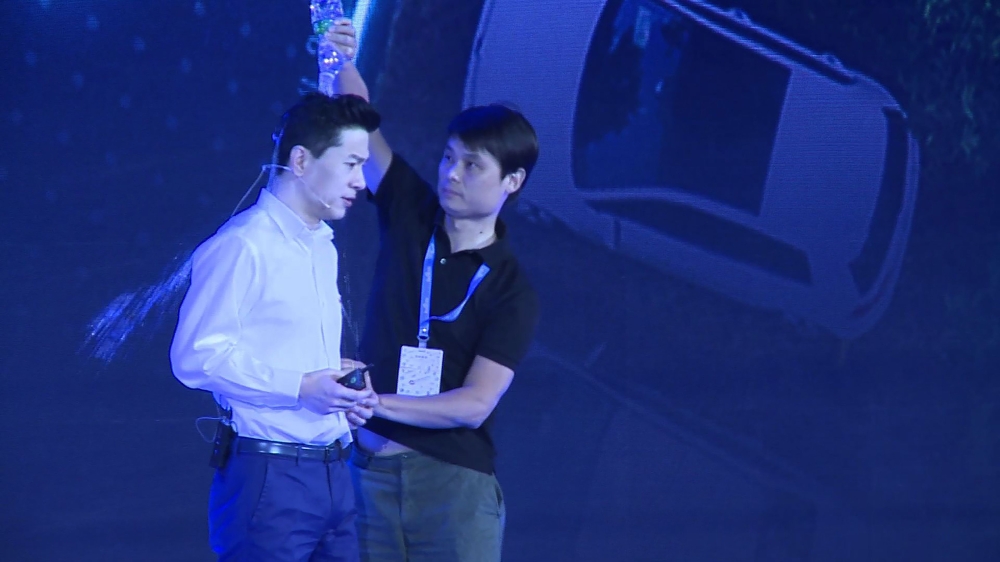 This framegrab taken from AFPTV shows a man (R) pouring water Baidu co-founder and CEO Robin Li during Baidu Create 2019 in Beijing on July 3, 2019. AFP / AFPTV / QIAN Ye