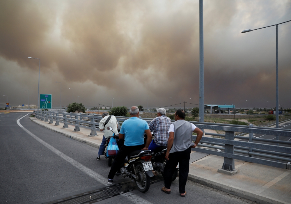 FILE PHOTO: People look at smoke as a wildfire burns in Kineta near Athens, Greece, July 23, 2018. Reuters/Alkis Konstantinidis