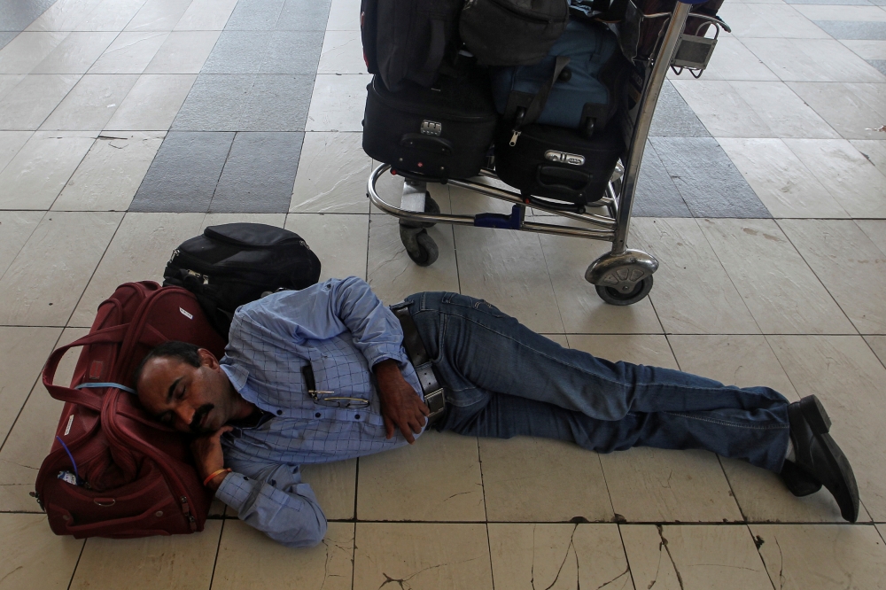 A stranded passenger sleeps next to his luggage as he waits for the delayed flight after an airplane overshot the runway while landing due to heavy rains at the Chhatrapati Shivaji International airport in Mumbai, India July 2, 2019. Reuters/Prashant Wayd