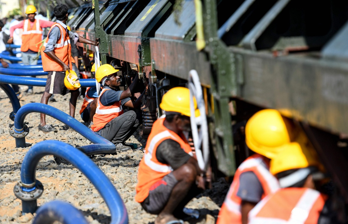 Labourers connect pipes to collect water from a special train of 50 wagons carrying litres of water at Villivakkam railway station in Chennai on July 12, 2019.  AFP / Arun Sankar 