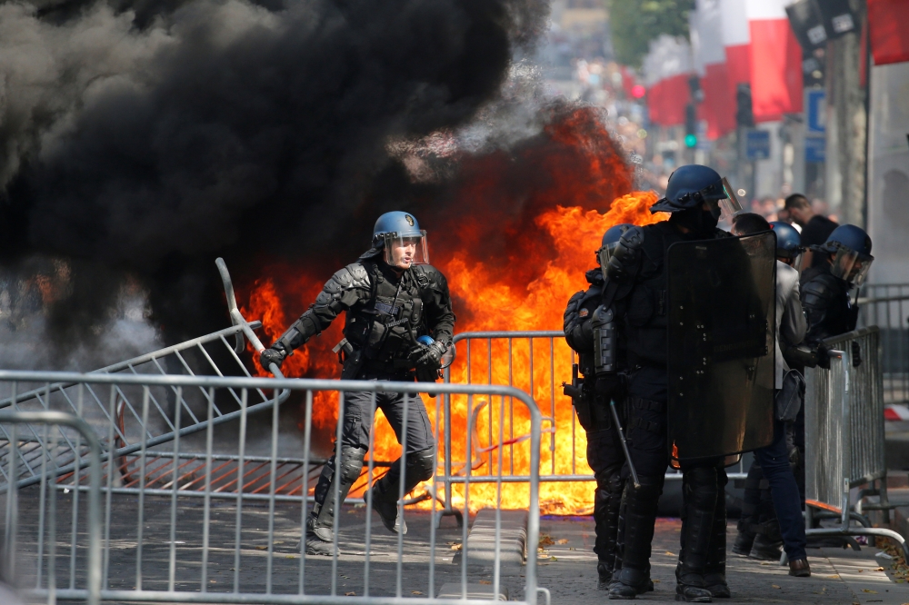 French Gendarmes remove fences next to a burning portable toilet during clashes with protesters on the Champs Elysees avenue after the traditional Bastille Day military parade in Paris, France, July 14, 2019. Reuters/Pascal Rossignol