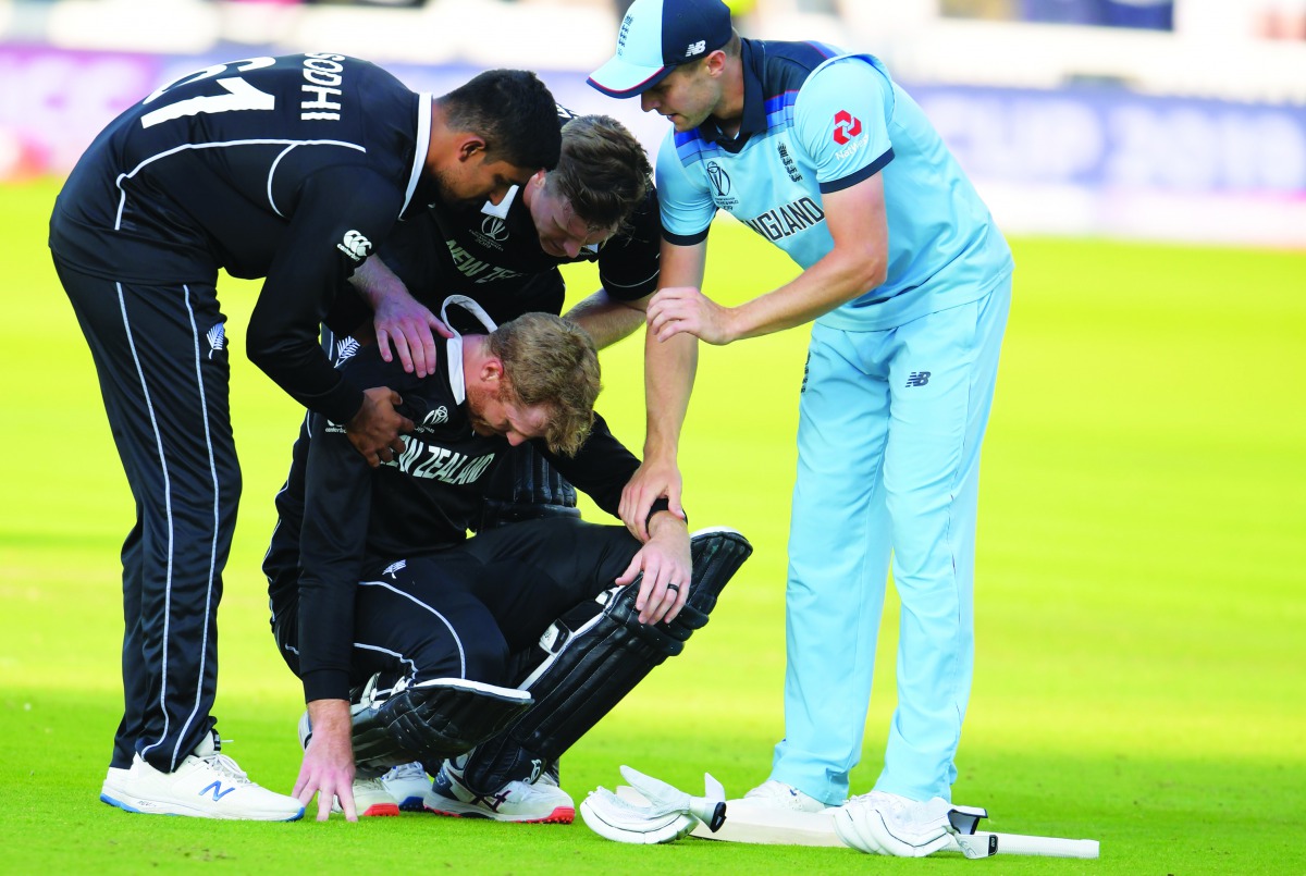 New Zealand's Martin Guptill (C) is assisted by teammates and England's Chris Woakes (R) after the 2019 Cricket World Cup final between England and New Zealand at Lord's Cricket Ground in London on July 14, 2019.  AFP / Dibyangshu Sarkar