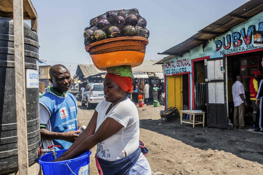 A woman washes her hands with chlorine as a health worker mans a washing station on July 15, 2019 in Goma. AFP / Pamela Tulizo 