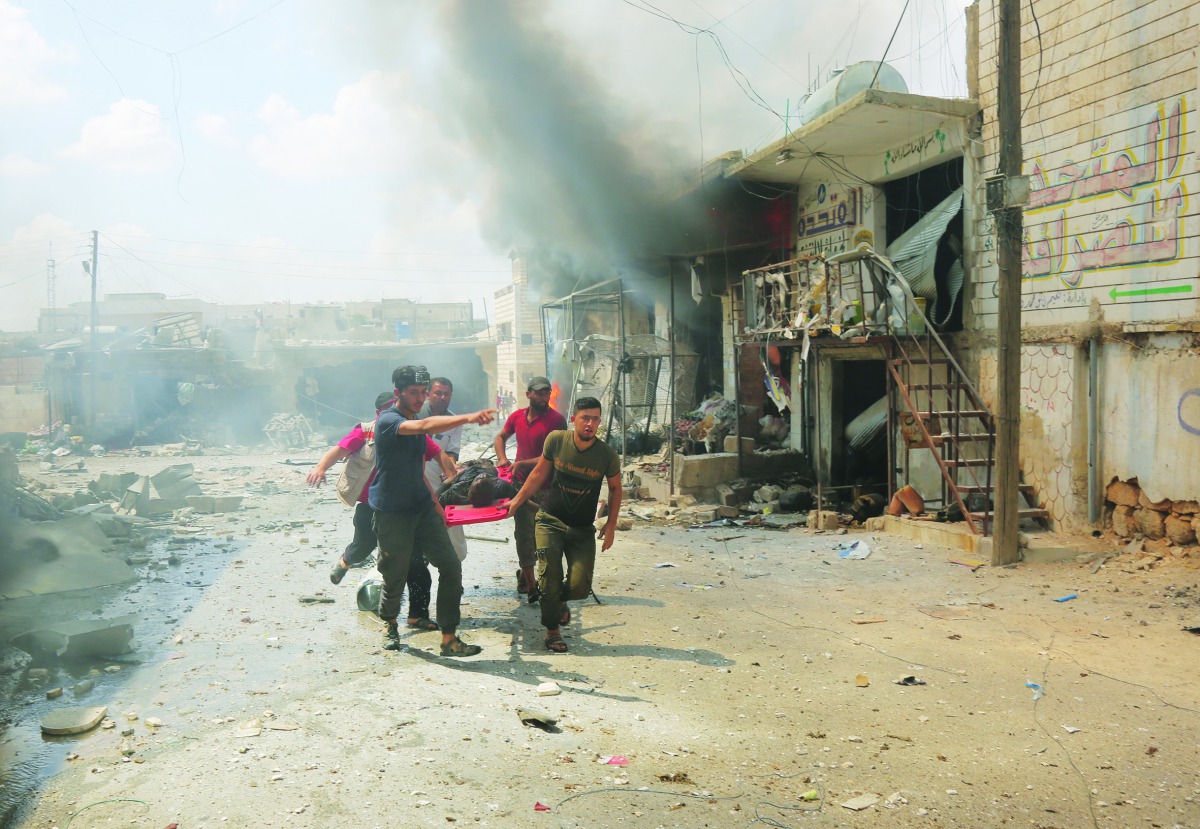 Civil defence crew members carry an injured person away from the scene after airstrikes by Assad Regime hit the de-escalation zone of Maar Shurin village in Idlib, Syria on July 16, 2019. At least 9 civilians were killed and 14 injured. (Izeddin Idilbi/An