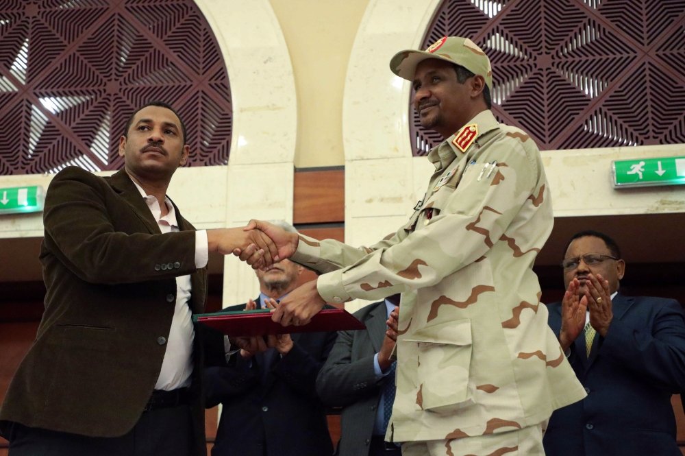 Deputy Head of Sudanese Transitional Military Council, Mohamed Hamdan Dagalo and opposition alliance signed coalition's leader Ahmad al-Rabiah shake hands after signing a political accord as part of a power-sharing deal aimed at leading the country to dem