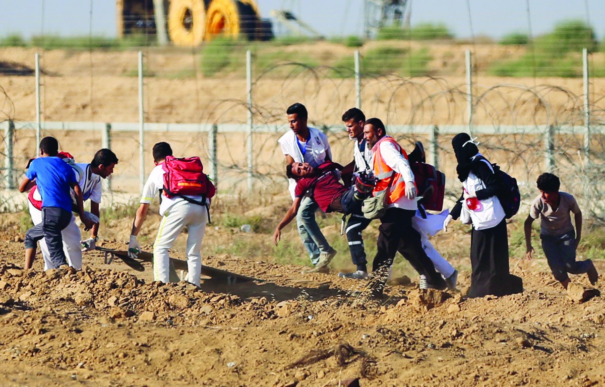 An injured Palestinian demonstrator is being moved away from the site after the intervention of Israeli forces during a demonstration within the 