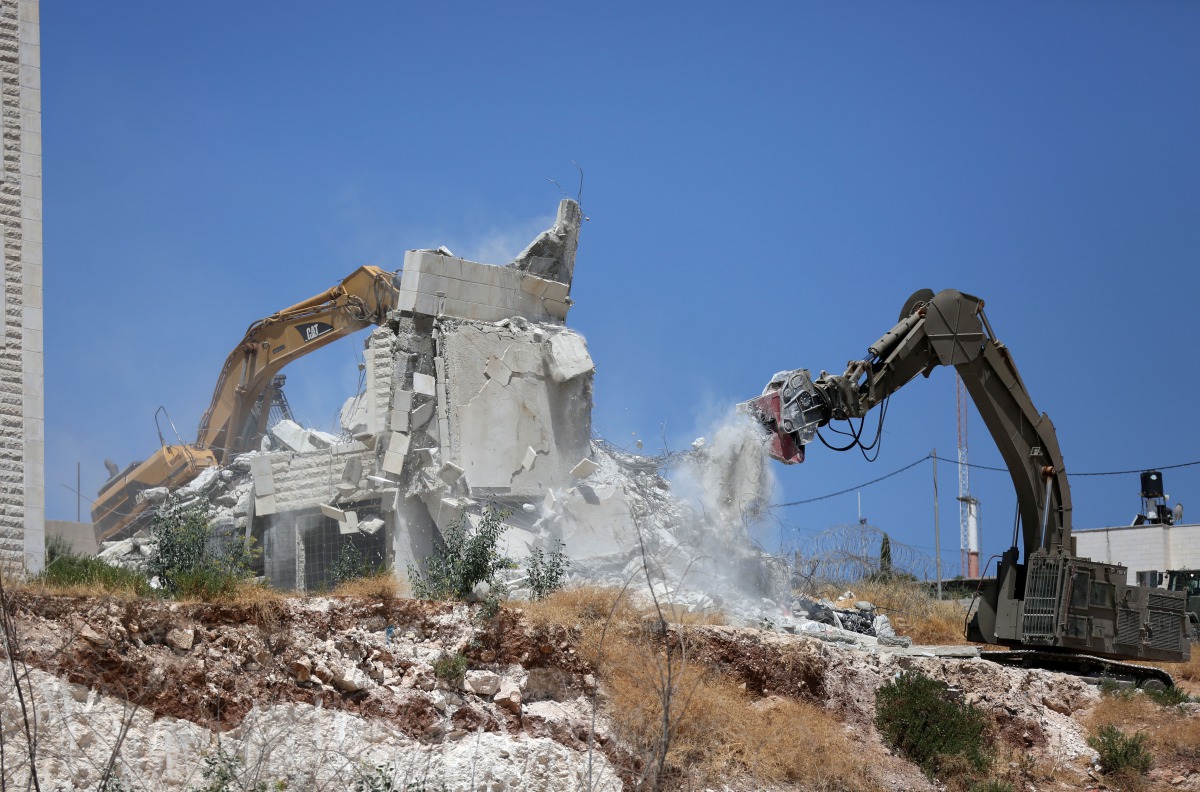 This picture taken from Jerusalem on July 22, 2019 shows Israeli security forces tearing down one of the Palestinian buildings still under construction which have been issued notices to be demolished in the West Bank village of Dar Salah, adjacent to the 