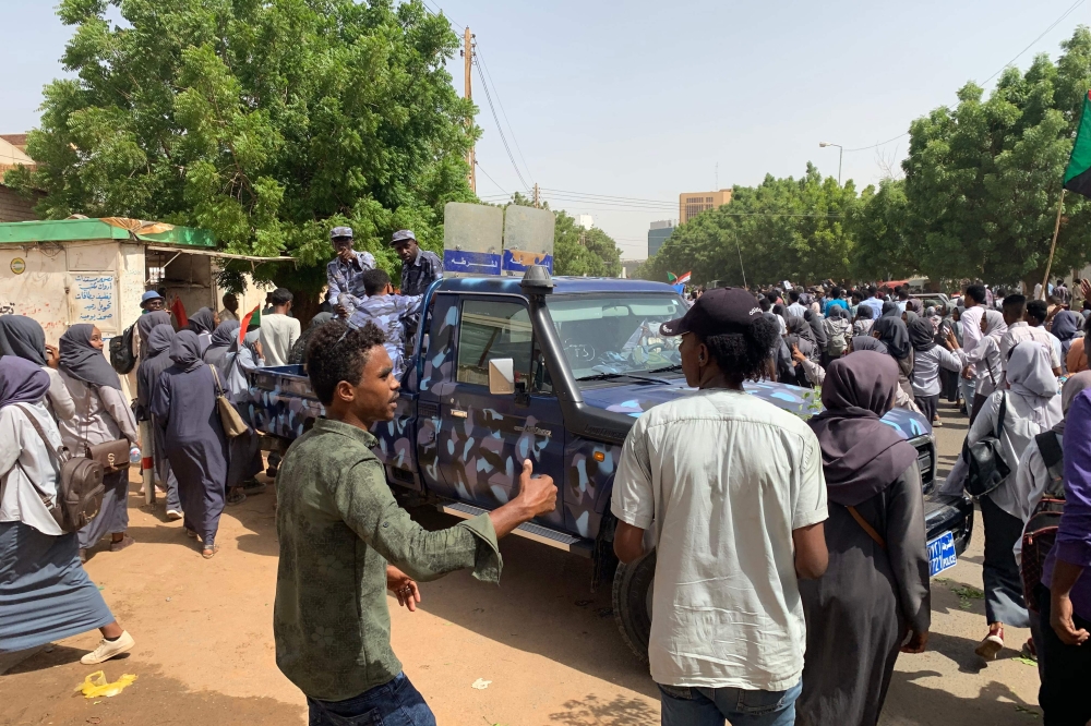 Sudanese protesters march past a security forces' vehicle during a demonstration commemorating protesters killed in past clashes, in the centre of the capital Khartoum on July 23, 2019. / AFP / Haitham EL-TABEI