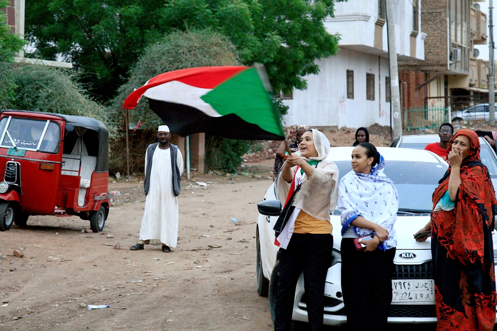 Sudanese demonstraters wave their national flag as they celebrate in Khartoum early on August 3, 2019, after Sudan's ruling generals and protest leaders reached a 