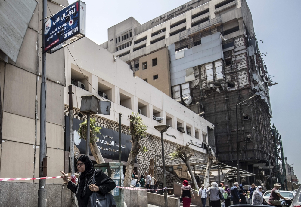 Egyptians walk outside the National Cancer Institute in the capital Cairo on August 5, 2019, where an accident took place just before midnight the previous day.   AFP / Khaled DESOUKI
