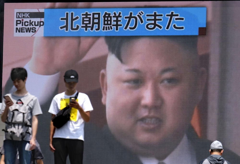 Pedestrians walk past a giant screen in Tokyo reporting about North Korea's missile launch earlier in the day, on August 10, 2019. (AFP / Kazuhiro NOGI)