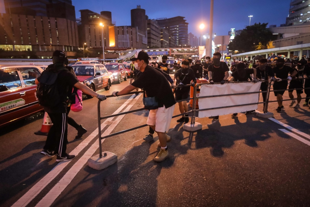 Protesters move barricades to block the entrance to the Cross-Harbour Tunnel after taking part in a rally against a controversial extradition bill in Hong Kong on August 10, 2019.  AFP / VIVEK PRAKASH