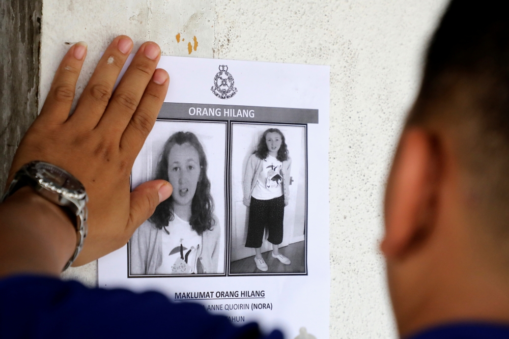 File photo of a police officer pasting a photo of 15-year-old Irish girl Nora Anne Quoirin who went missing from a resort on a wall at a shop in Seremban, Malaysia, August 9, 2019. REUTERS/Lim Huey Teng