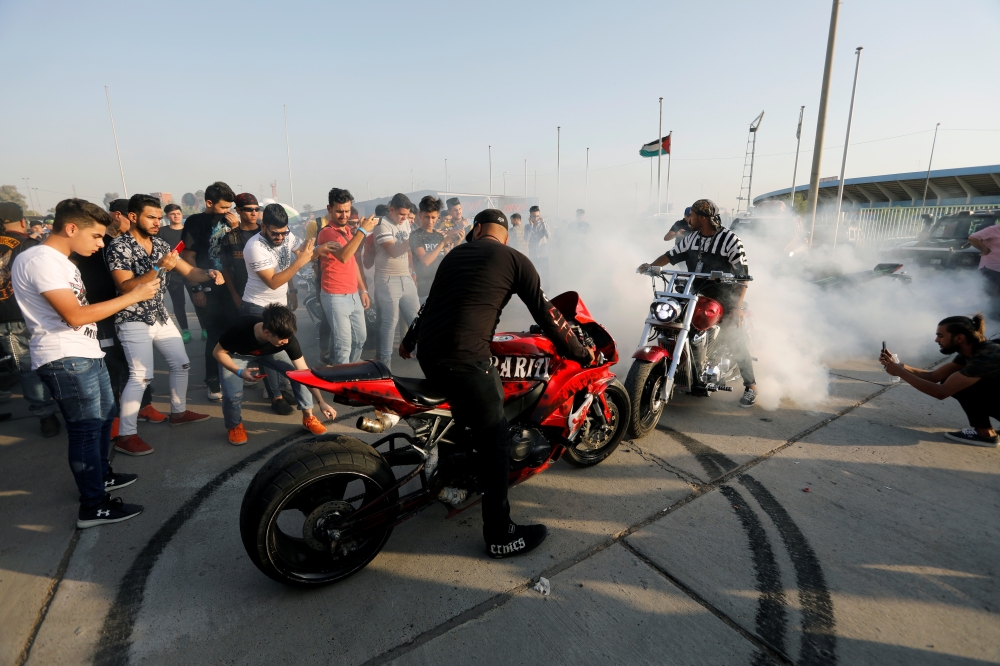 A biker wheelspins on his motorbike during a car and motorbike show outside the closed Hall of Shaab Stadium in Baghdad, Iraq August 16, 2019. Picture taken August 16, 2019 REUTERS/Thaier Al-Sudani