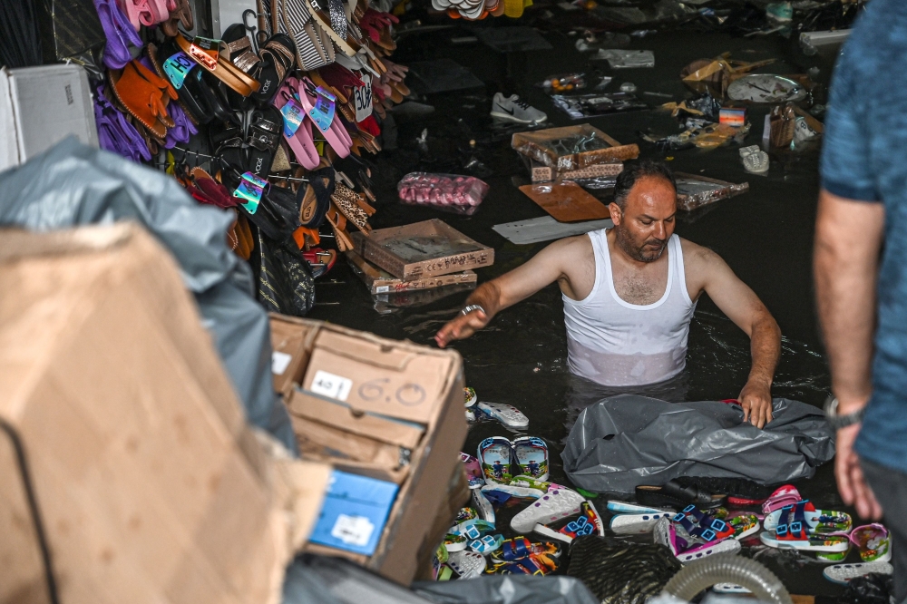 A shop owner tries to save his belongings in a flooded undergate shop center on August 17, 2019 in Eminonu district in Istanbul, after a heavy rainfall.   AFP / Ozan KOSE