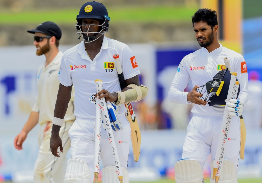 Sri Lanka's cricketer Angelo Mathews (C), teammate Dhananjaya de Silva (R) and New Zealand's cricket captain Kane Williamson (L behind) leave the field after Sri Lanka beat New Zealand in first Test by six wickets during the final day of the opening Test 