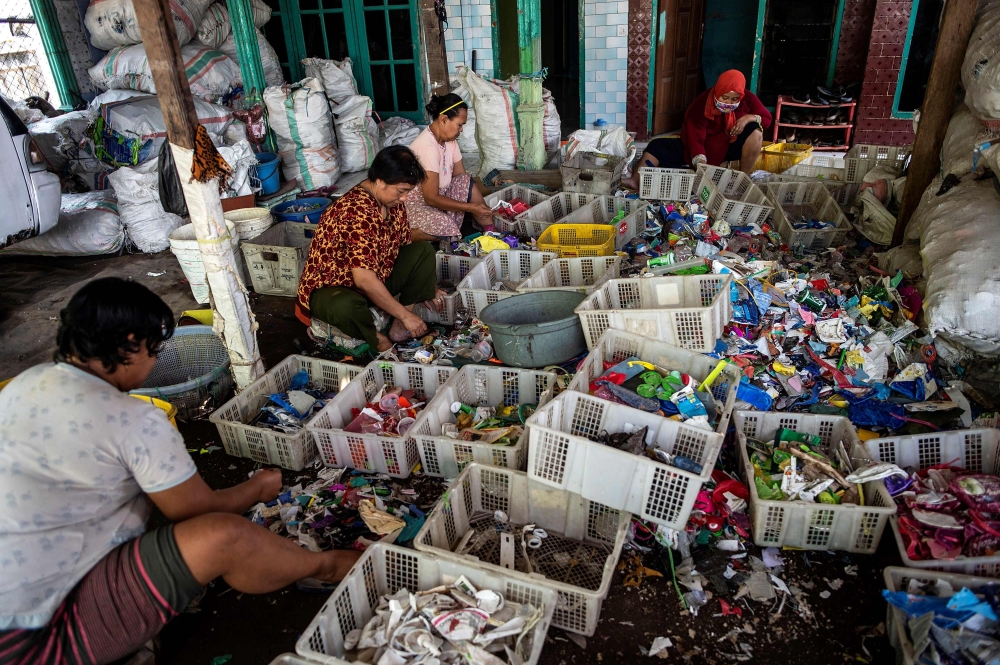 This picture taken on July 22, 2019 shows villagers sifting through plastic waste in the village of Bangun.  / AFP / Juni Kriswanto / 