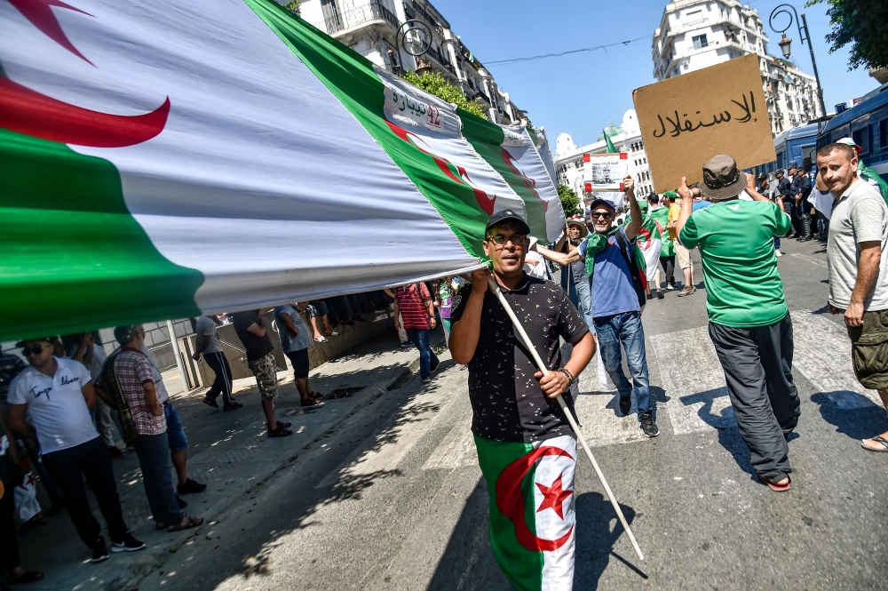 Algerian demonstrators chant slogans and march with national flags as they gather in the streets of the capital Algiers against the ruling class amid an ongoing political crisis in the country, on the 26th consecutive Friday of protests on August 16, 2019