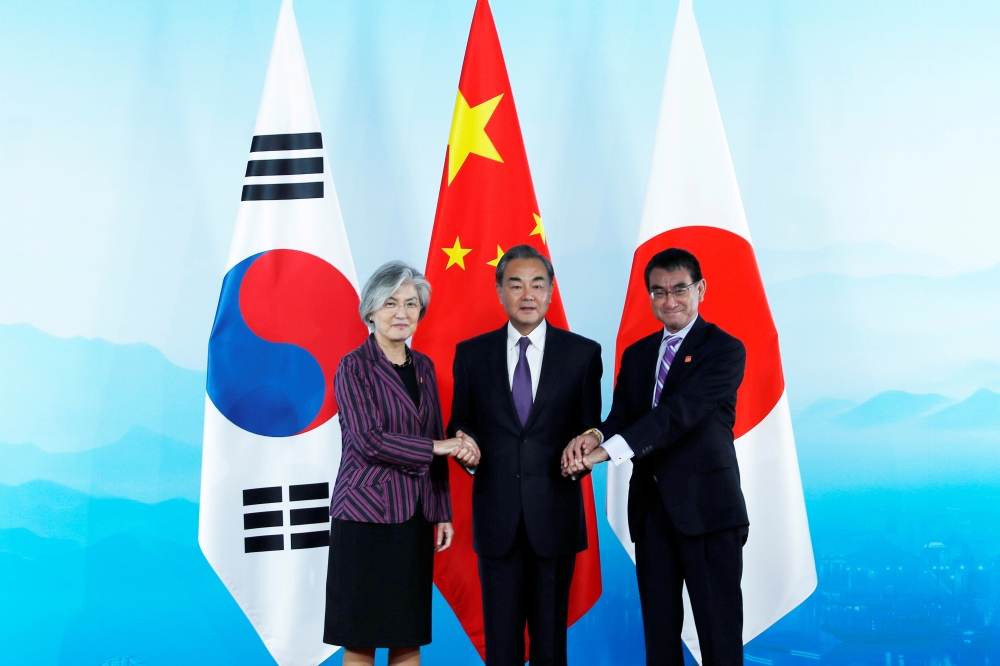 Chinese Foreign Minister Wang Yi (C), South Korean Foreign Minister Kang Kyung-wha (L) and Japanese Foreign Minister Taro Kono (R) shake hands ahead the ninth trilateral foreign ministers' meeting among China, South Korea and Japan at Gubei Town in Beijin