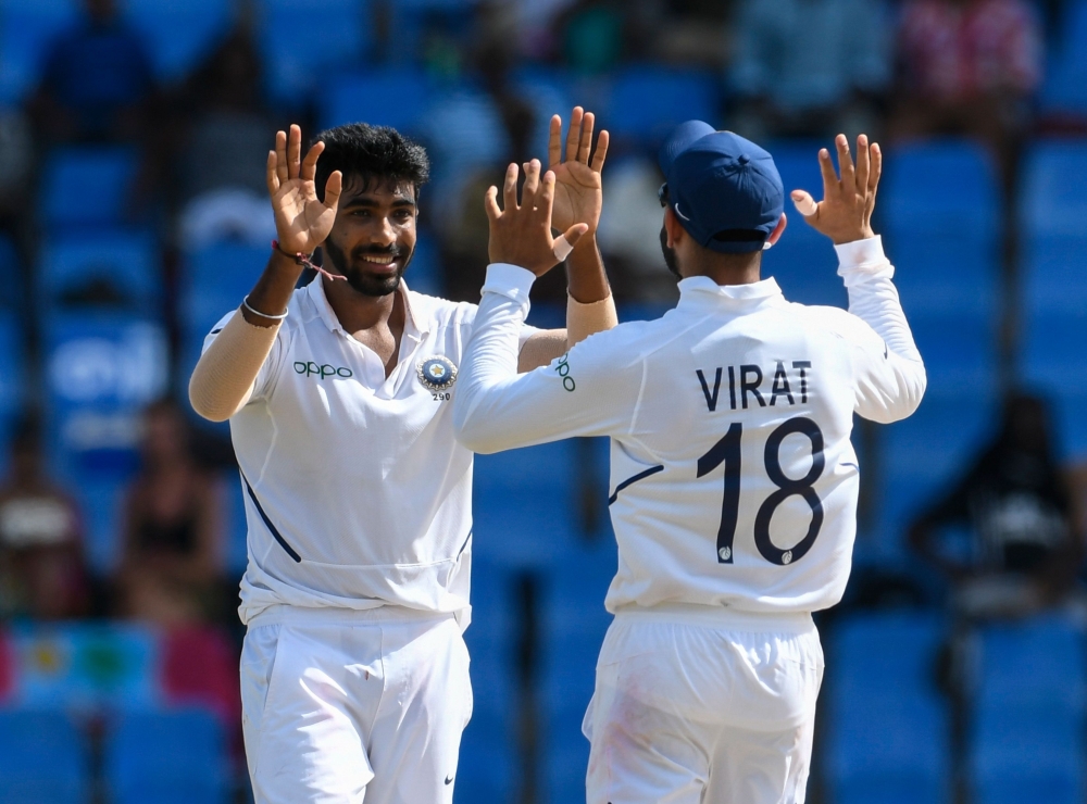 Ravindra Jadeja (L) and Virat Kohli (R) of India celebrate the dismissal of Sharmarh Brooks of West Indies during day 2 of the 1st Test between West Indies and India at Vivian Richards Cricket Stadium in North Sound, Antigua and Barbuda, on August 23, 201