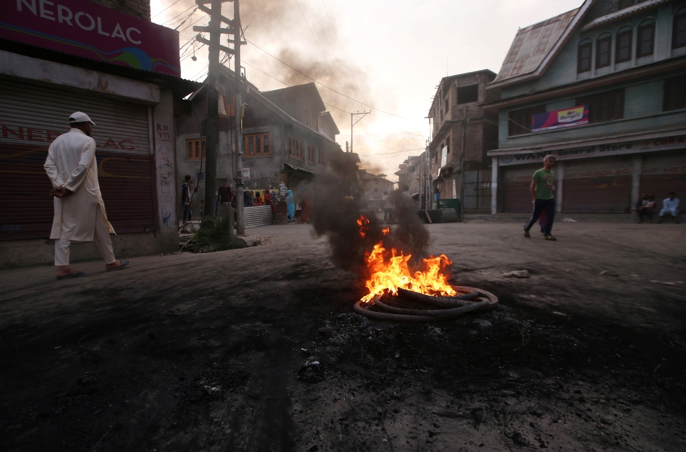 Kashmiri people walk past burning tyres during a protest after the scrapping of the special constitutional status for Kashmir by the Indian government, in Srinagar, August 27, 2019. Picture taken on August 27, 2019. REUTERS/Danish Ismail