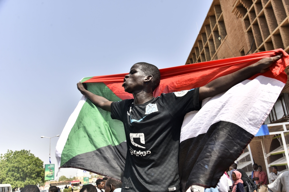 A Sudanese man spreads a national flag in Omdurman as he takes part in a rally in solidarity with Ahmed al-Kheir, a young Sudanese who died in custody after his arrest in January on allegations of organising anti-Bashir protests, on August 28, 2019.  AFP 
