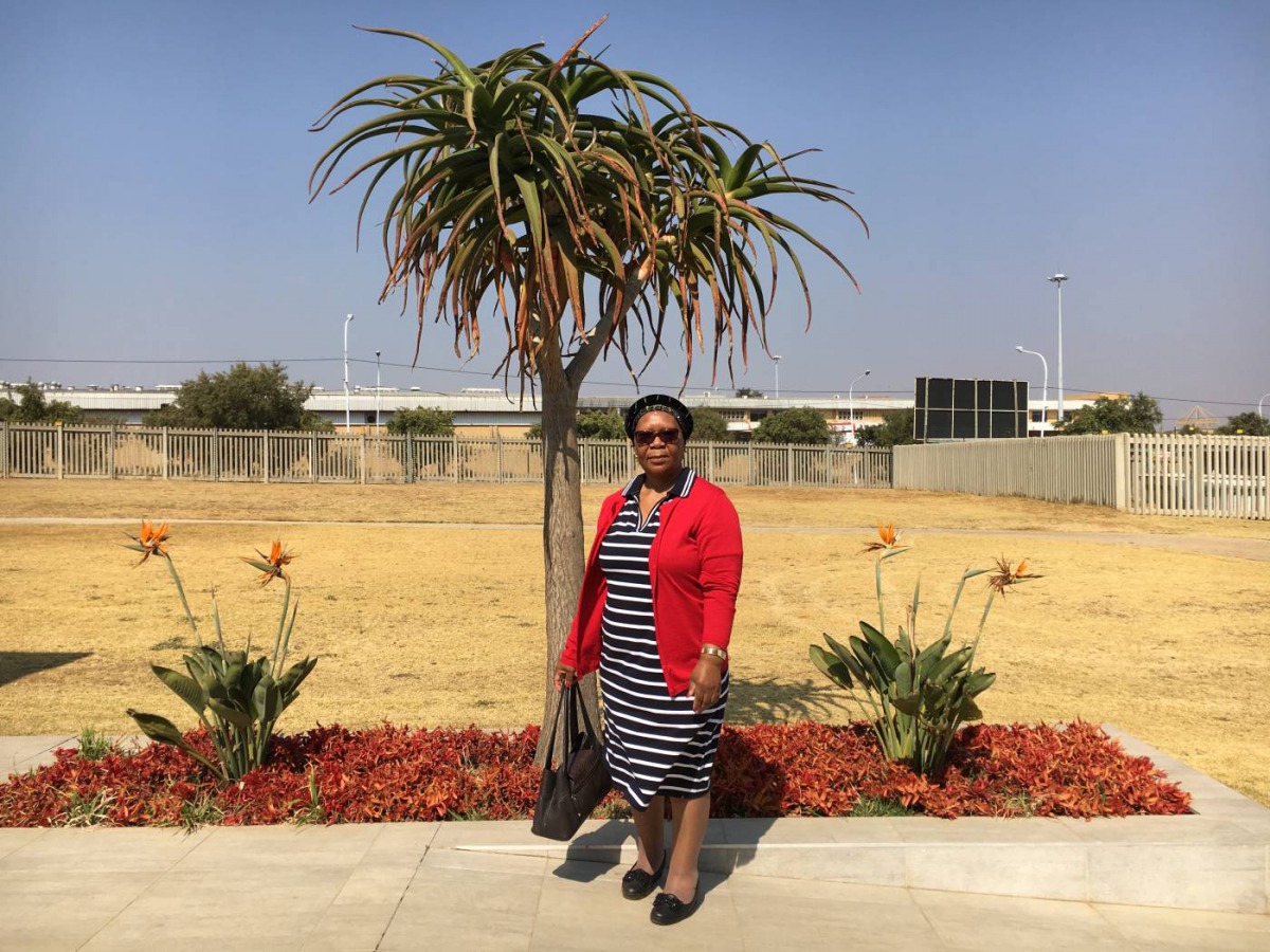 Mmaphuti Singo stands in front of some of the fauna planted through the Nasrec Memorial Park in Soweto, Johannesburg, South Africa, where she buried her husband last year, August 8 2019. Thomson Reuters Foundation/Kim Harrisberg.