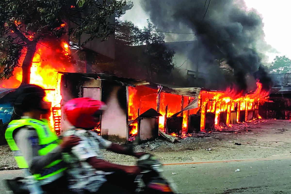 A motorist ride past a burning building after hundreds of demonstrators marched near Papua's biggest city Jayapura on August 29, 2019, where they set fire to a regional assembly building and hurled rocks at shops and hotels. AFP / Indra Thamrin Hatta

